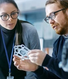 Cientistas de materiais em um laboratório de ciência de materiais examinam um protótipo impresso em 3D.