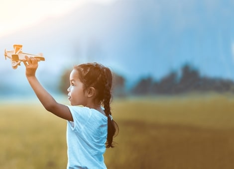 Girl with airplane toy in field