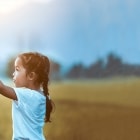 Girl with airplane toy in field