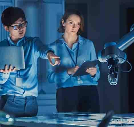 Engineers in a design lab discuss AI production solutions for using a factory robot.