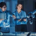 Engineers in a design lab discuss AI production solutions for using a factory robot.