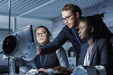 Engineering team watches product videos on a laptop computer.