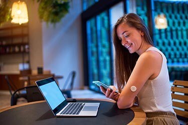 Woman in cafe uses smart technology to monitor her health with a smartphone.