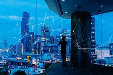 Ein Mann spricht in ein Smartphone, während er eine 5G-verbundene intelligente Stadt betrachtet.