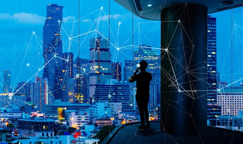 Man looks at cell phone with connected city in background.