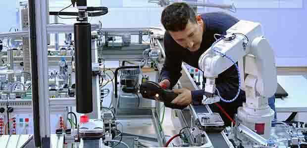 工場で工場用協働ロボットと作業をするエンジニア。