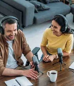 Mann und Frau sitzen an einem Tisch und sprechen in einem Podcast über Technik.