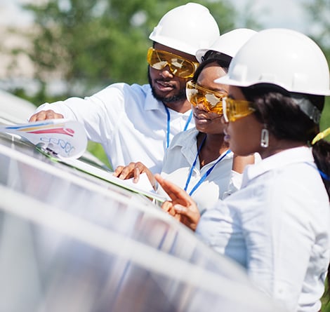 Three engineers review design materials for a solar energy collection system.
