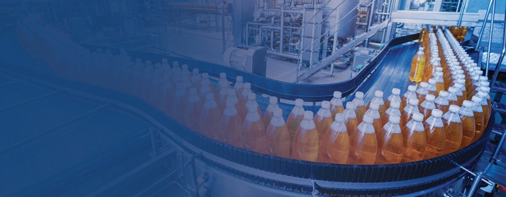 Garrafas envasadas com um líquido laranja movendo-se por uma instalação de linha de produção. 