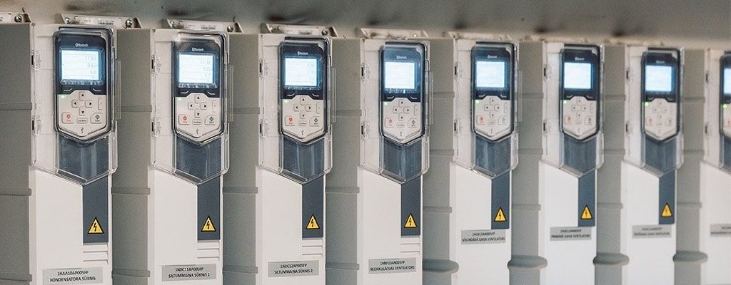 A row of industrial variable speed drives (VSDs) mounted side-by-side in a blue-toned, perspective-view photograph.