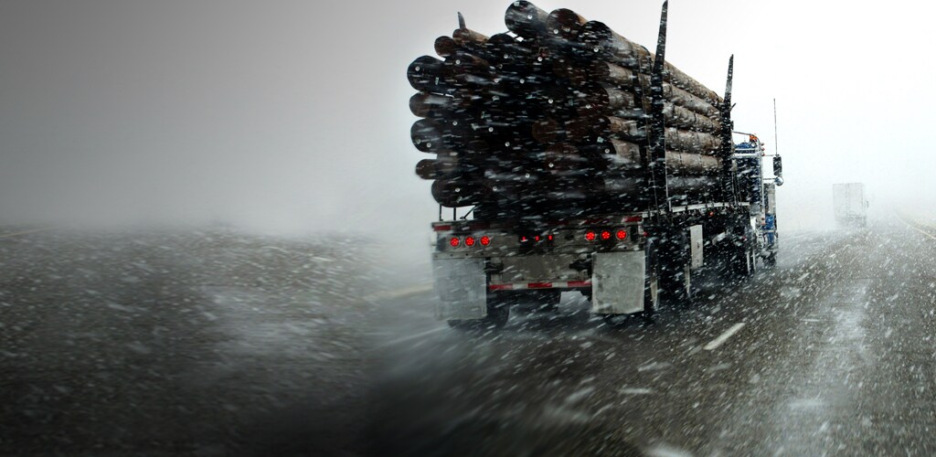 A heavy duty truck on the highway, during a snow storm.